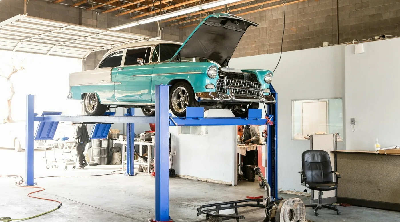 A turquoise 1955 Chevrolet Bel Air on a lift inside the Arizona's Reliable Transmissions shop