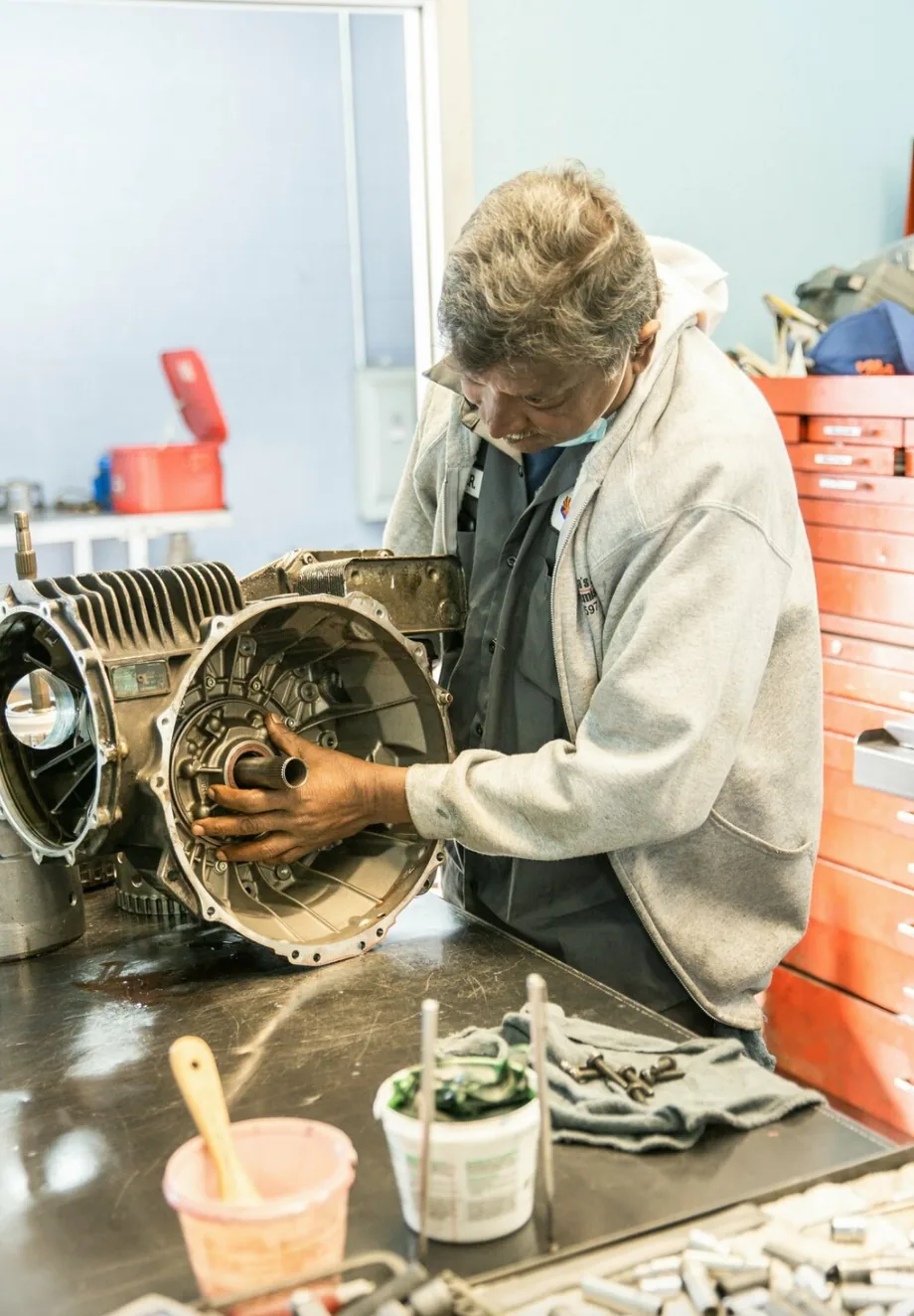 A technician rebuilding a transmission at a workbench inside the shop